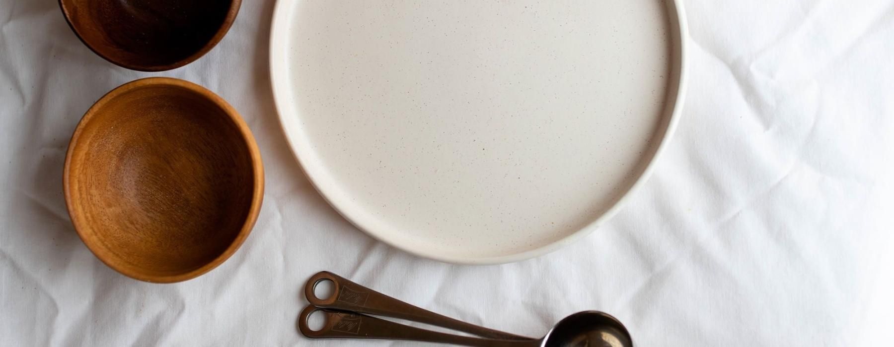 bowls, a plate and measuring spoons arranged neatly on cloth