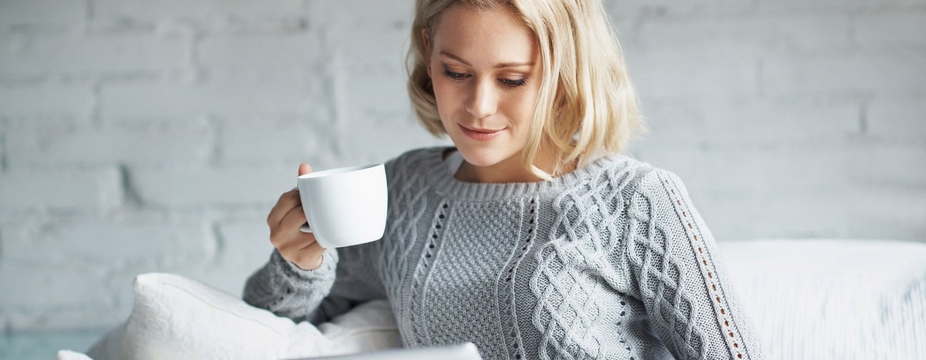 a woman sitting on a sofa with a cup of coffee